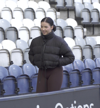 woman walking along football stadium aisle